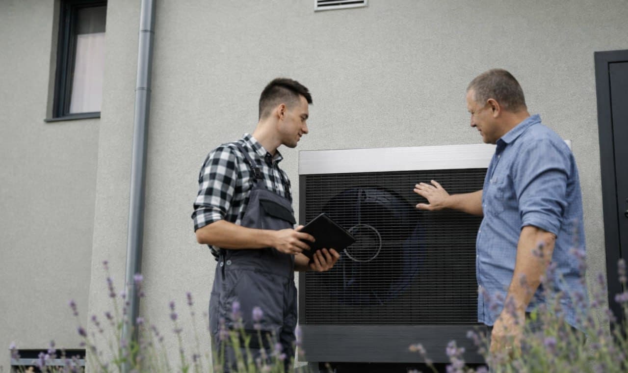 Trident installer and customer in front of a heat pump